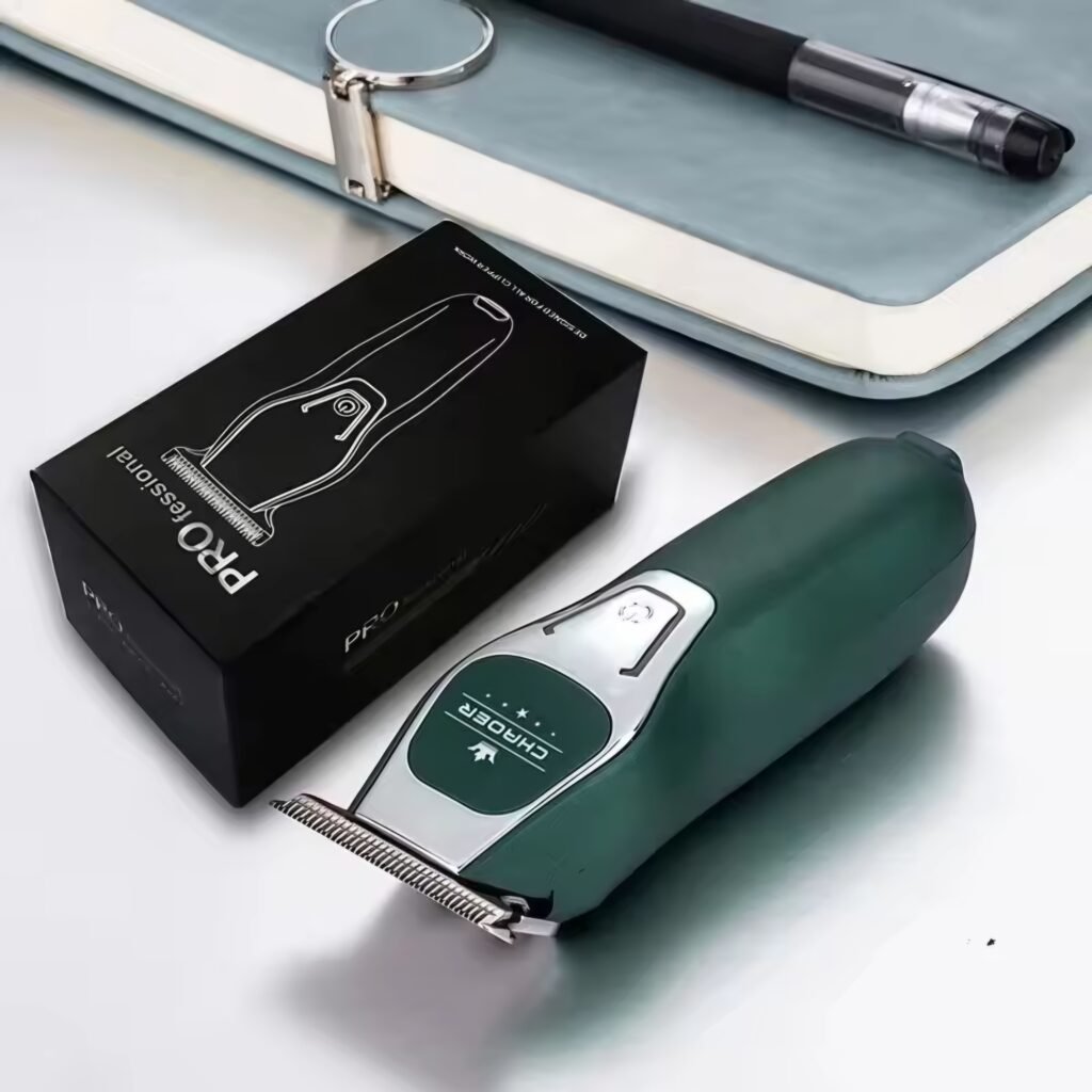 The green CHAORER portable hair clipper placed on a desk next to its box and keychain, showing its travel-friendly design.